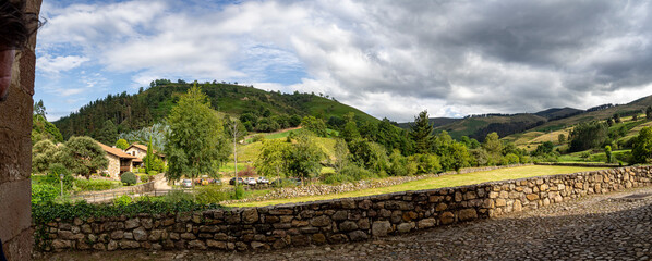 Vistas del paisaje de naturaleza con nubes oscuras, bosque verde y un muro de piedra en el pueblo de Carmona en Cantabria , verano de 2020.