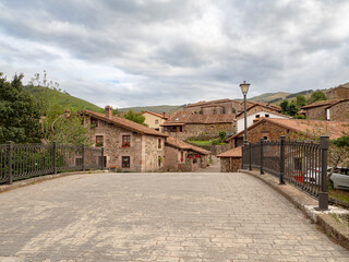 Fototapeta na wymiar Vista del paisaje de cielo nublado y de casas antiguas de piedra en el pueblo de Carmona, en la Cantabria rural de España, verano de 2020