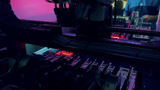 Automated SMT Pick and Place Production of Motherboards and Computer Chips. Head on an arm founds reels, tubes, circuit and picks them up and then places them onto the board