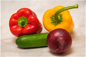 Still life with fresh ripe vegetables: red and yellow paprika, red onion and green cucumber