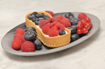 Delicious cace decorated with raspberries, bluberries and brush red currant