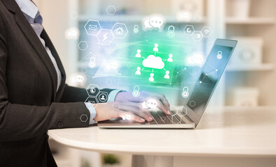 Hands working on laptop with digital icons