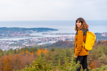 Naklejka premium A young woman looking from the top of Erlaitz over the Bidasoa river and the municipalities of Fuenterrabia and Hendaya in the town of Irun, Gipuzkoa. Basque Country