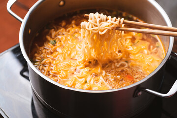 Asian spicy instant noodles soup cooking in hot pot with chopsticks