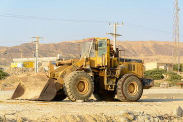 Fototapeta na wymiar chabahar, iran 27 october 2021, Big yellow front-end loader or all wheel bulldozer, side view from yellow rusty loader parked with opened door