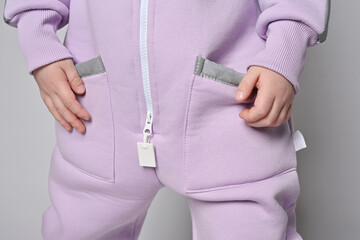 Closeup of kid girl in pink jumpsuit with zipper and holding hand in pocket with retroreflective...