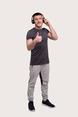 Fototapeta premium Sport Man Standing Listening to Music and Enjoys Watching to Camera Showing Thumb Up. Trainer Listening Music. Good Music. man relaxing. Music for Sport