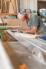 Worker noting measurements on a sliding table saw