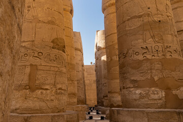 Colonnade in the ancient Egyptian temple of Horus in Luxor.  Hieroglyphs are visible on the thick columns, scenes from the life of the gods are carved.  Blue sky. A sunny day.