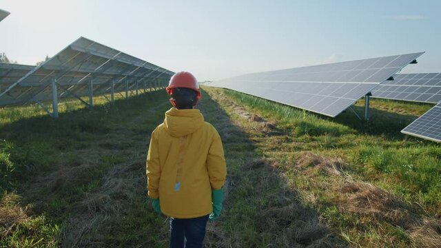 Young boy teenager wearing helmet and gloves walking on solar panel construction. Photovoltaic cells. Solar eco-friendly station. Alternative energy. Excursion.