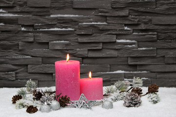 Weihnachtshintergrund. Rosa Kerzen mit Weihnachtschmuck vor einer Mauer.