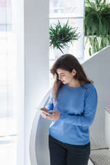 Attractive young woman in a blue sweater uses the phone.