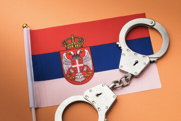 Serbian flag and handcuffs on a colored background, the concept of crime in Serbia, top view