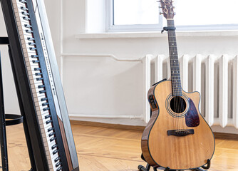 Piano keys and acoustic guitar in the interior of a bright room.