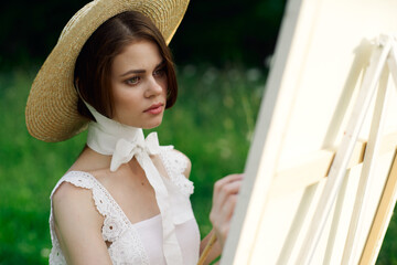 woman artist in hat with brush paints a picture