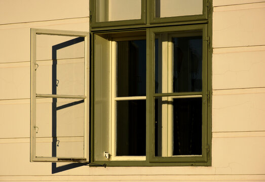 painted green wood window. beige stucco elevation. old classic architecture. decorative facade. buildings and archiecture concept. travel and tourism. urban detail in Europe. bright light with shadows