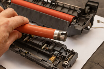 a view of a worn out upper heating shaft, roller from a printer in the hand of a person, a service...