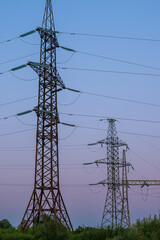Pylons and high-voltage power lines at sunset. Industrial landscape. The concept of the energy crisis in Europe.