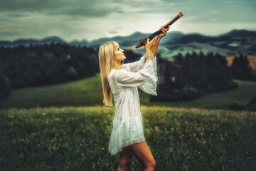 girl playing on shaman flute in the nature.