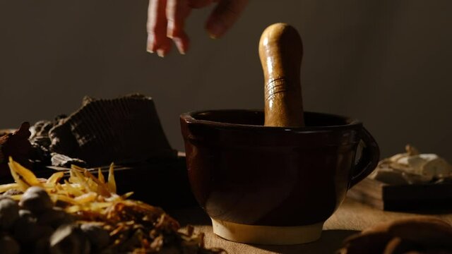 Chinese traditional medicine with herb and spices and doctor is pulping the herb by using a ceramic bowl , front view for advertising , traditional medicine content