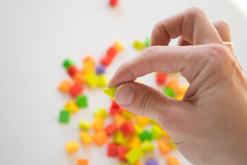 He holds a lot of colorful plastic parts of the designer in his hands. Rainbow elements in the hands. Choosing a future profession for a child. Methods of early child development