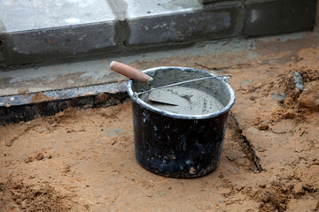 Bucket with cement and a trowel when building foundation blocks. Concept of building a new home