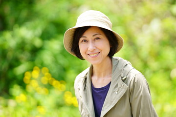 緑の中で帽子をかぶって立つ笑顔の中年女性　ポートレート