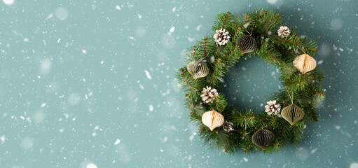 Christmas wreath with decoration on light blue green background, top view. Space for text