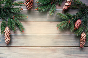 Christmas tree branches with pine cones on wooden background with copy space