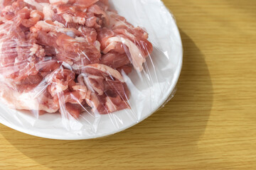 皿にのせてラップをかけた豚肉