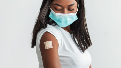 Vaccinated Black Female In Mask Showing Shoulder With Adhesive Bandage