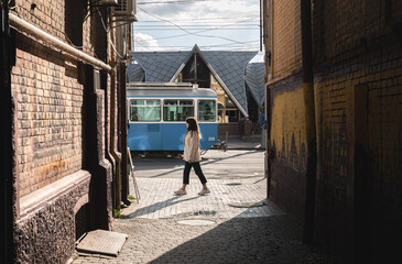 A woman walks down the street against the background of a passing tram.