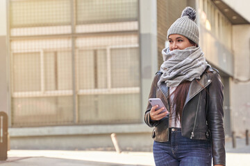 Glad female in outerwear using smartphone