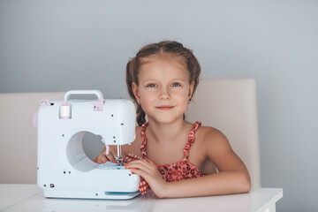 7 years old child studying work with a modern sewing machine. Hobby.