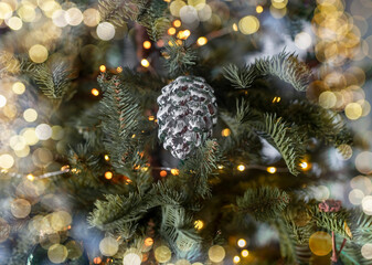 Obraz na płótnie Canvas Cone toy on fir tree. Christmas decor and lights.