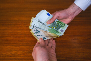 Money is being handed over. Euro banknotes as salary, present, bribe, or payment amount. 