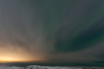 At night, fog and northern lights tundra and rocks in winter.