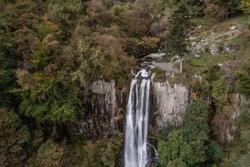 Obraz premium Aerial flying drone bird's eye view Beautiful long exposure landscape early Autumn image of Pistyll Rhaeader waterfall in Wales