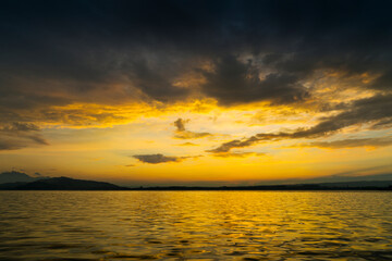 Obraz premium View of Lake Zugersee in the Swiss town of Zug at sunset with beautiful golden tones in the sky and reflected in the water and clouds.
