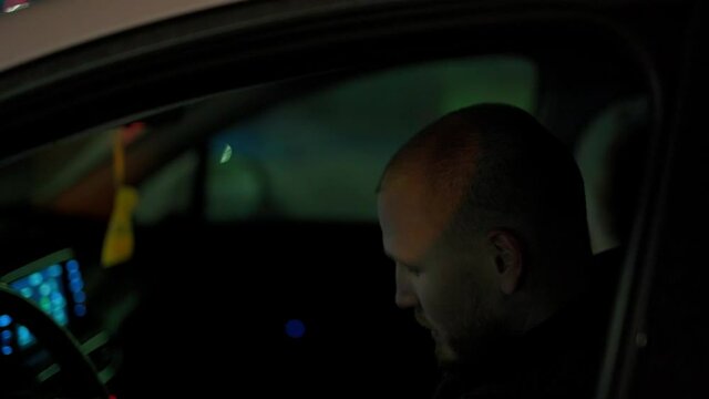 Russia,Yamalo-Nenets Autonomous Okrug, Novy Urengoy city, October 17, 2021, 22:00, a 35-year-old guy smokes a cigarette in the courtyard of a house in the Vostochny microdistrict at his white car