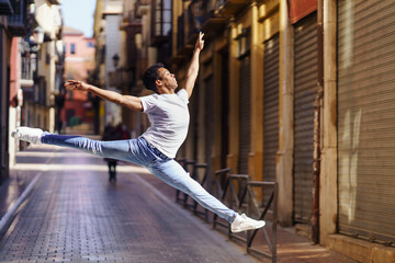Young black man doing an acrobatic jump in the middle of the street.