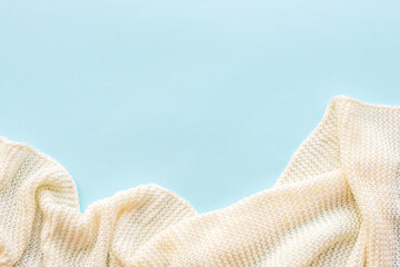 White knitted blanket on blue background. Top view, flat lay, copy space