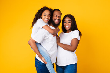 African American man posing with wife and smiling daughter