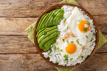 Arroz con huevo frito is white rice and a fried egg close up in the plate on the table. Horizontal top view from above