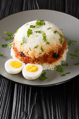 Arroz Tapado delicious filling, adaptable rice with beef, peppers, tomato, onion, and seasoning close up in the plate on the table. Vertical