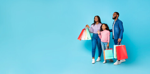 African American cheerful people holding shopping bags looking aside, panorama