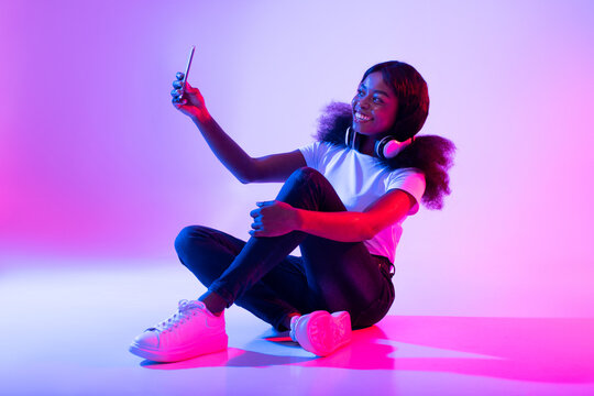 Photography Concept. Smiling Young Black Woman Taking Selfie In Neon Light, Full Length