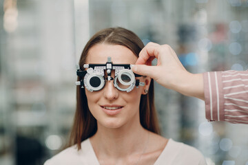 Portrait of happy young woman during eye exam at optometrist optician - obrazy, fototapety, plakaty