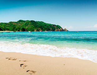 beach landscape with white sand and green hill