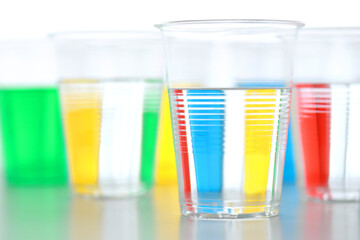 色の付いた水が入った瓶やコップ